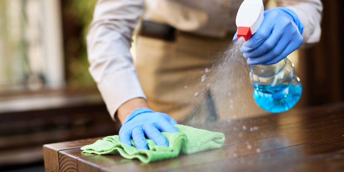 Close-up of waitress cleaning tables with disinfectant due to coronavirus epidemic.