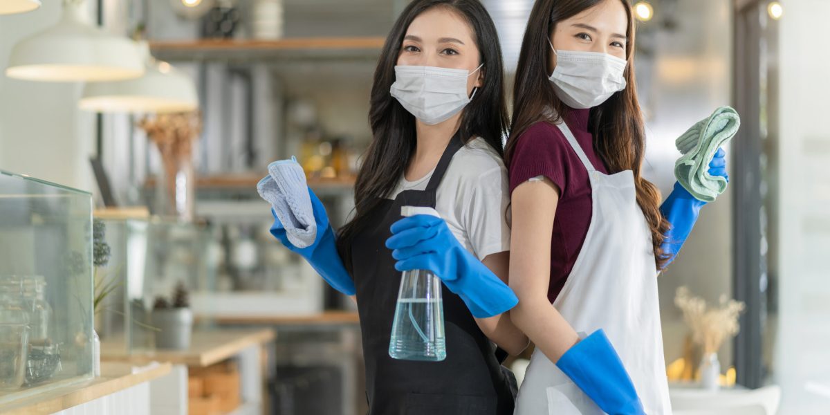 portrait of asian waitress with apron staff wearing protection rubber glove face mask protection hand hold cleaning towel and alcohol spray disinfectant for protect infection coronavirus health ideas